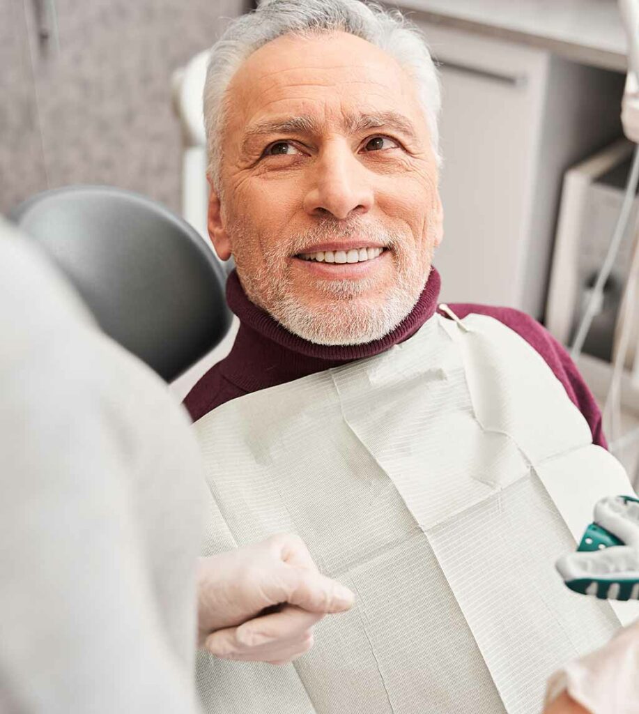 Senior man with white hair receiving a deep cleaning service in a dental chair at Fay Periodontics, enhancing oral health through expert periodontal care