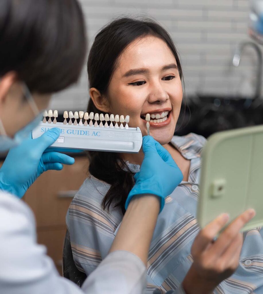 Patient at Fay Periodontics selecting the shade of veneers for her dental implants, ensuring a perfect match for a natural-looking smile.